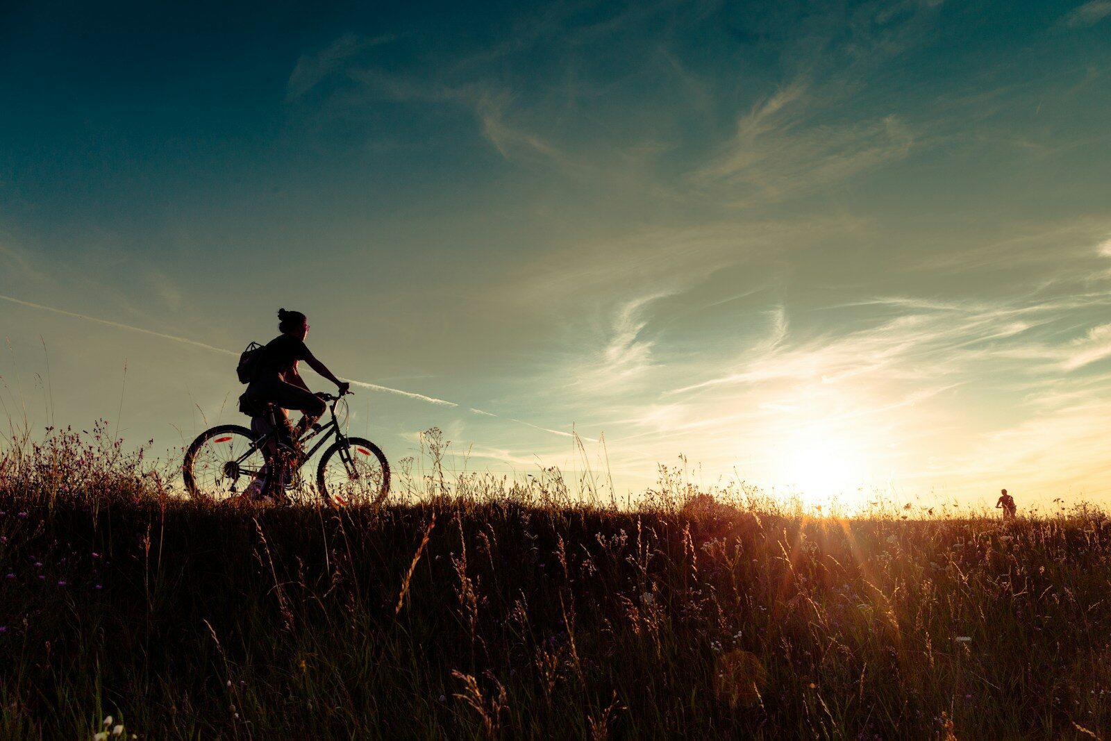 une personne roule a vélo au coucher de soleil